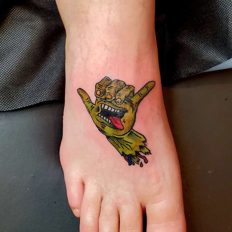 Colorful cartoon hand creature tattoo on foot