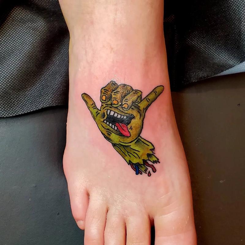 Colorful cartoon hand creature tattoo on foot