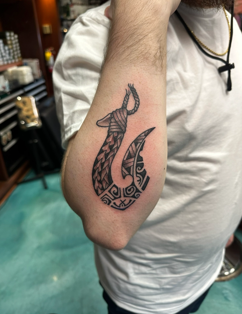 Blackwork tribal hook tattoo on forearm