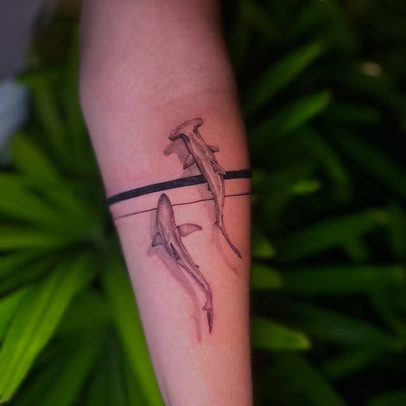 Black and grey illustrative shark tattoo on forearm