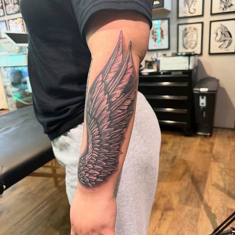 Black and grey wing tattoo on forearm