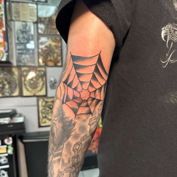 black spider web tattoo on forearm