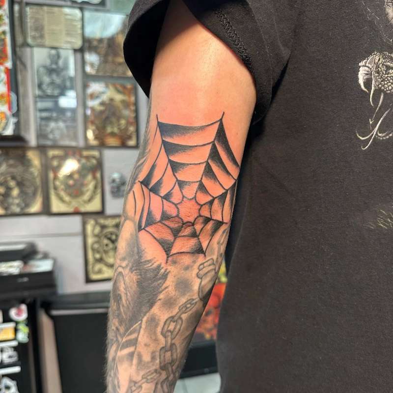 black spider web tattoo on forearm