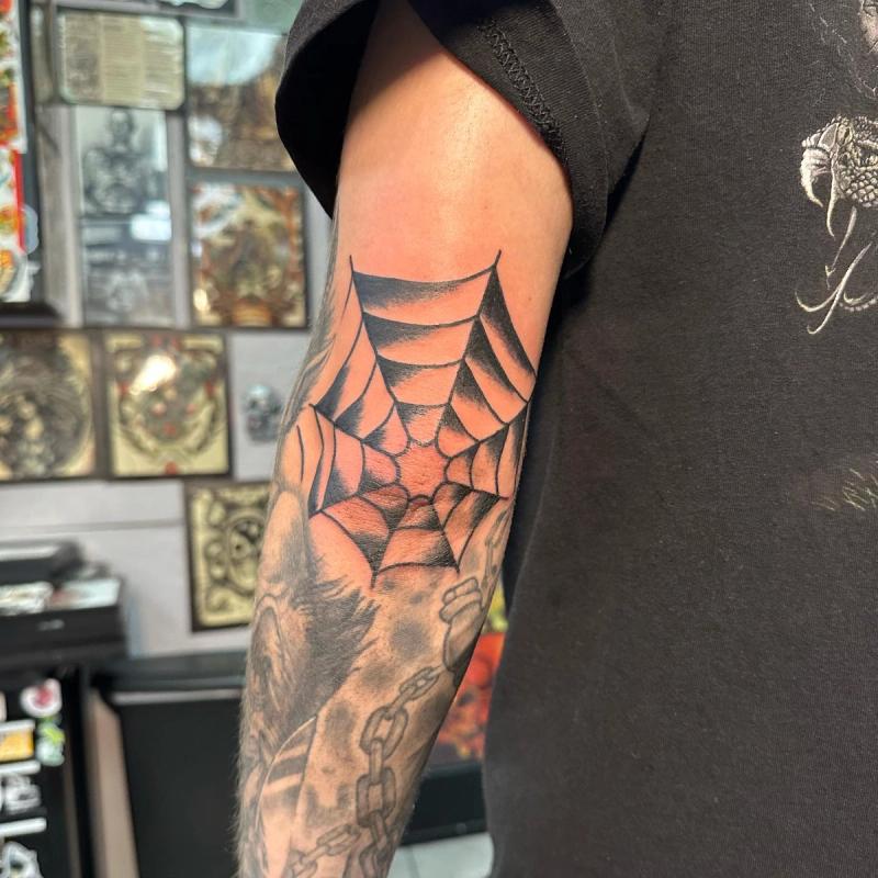 black spider web tattoo on forearm