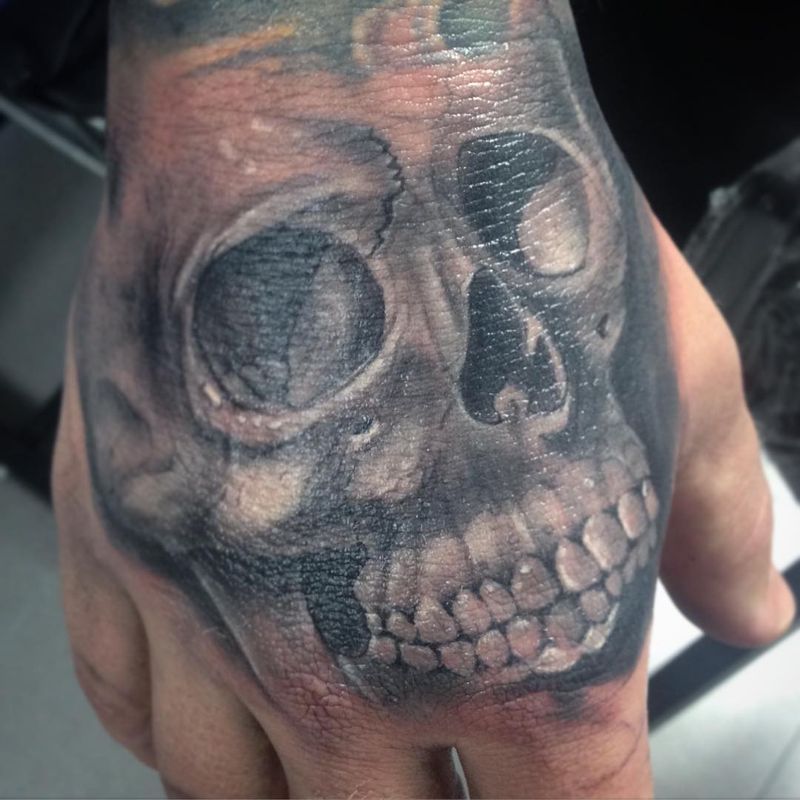 Black and grey realistic skull tattoo on hand