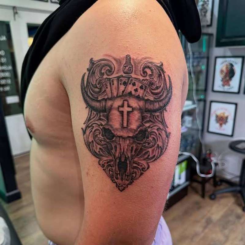 Black and grey illustrative skull with cards on upper arm