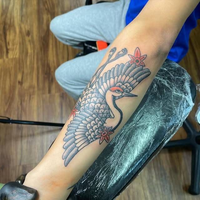 Colorful crane and flower tattoo on forearm