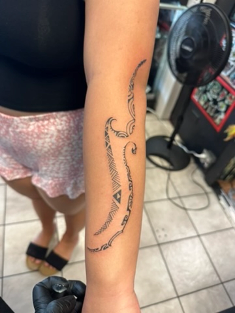 Black tribal patterned tattoo on forearm.