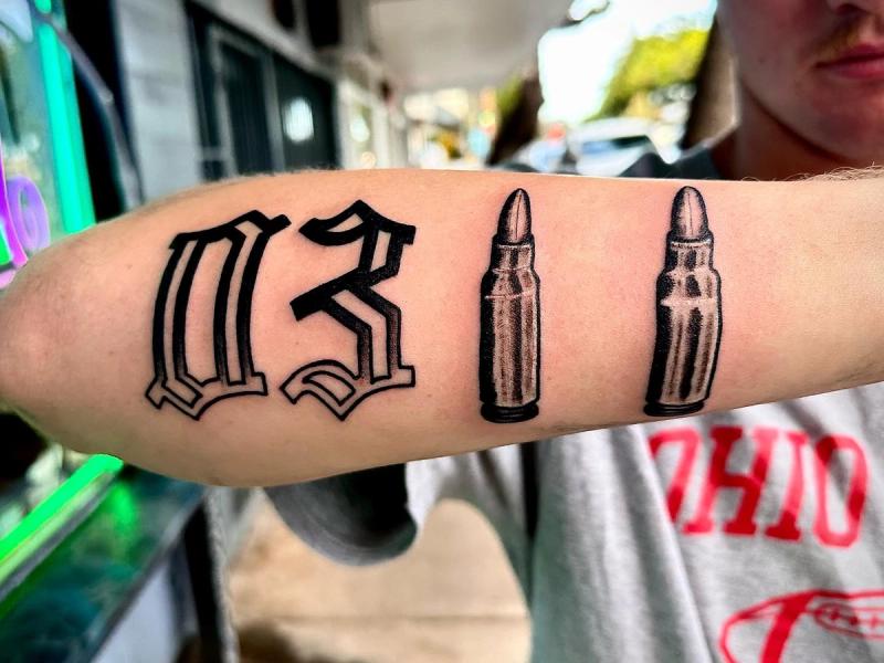 forearm tattoo with old english lettering and bullet design