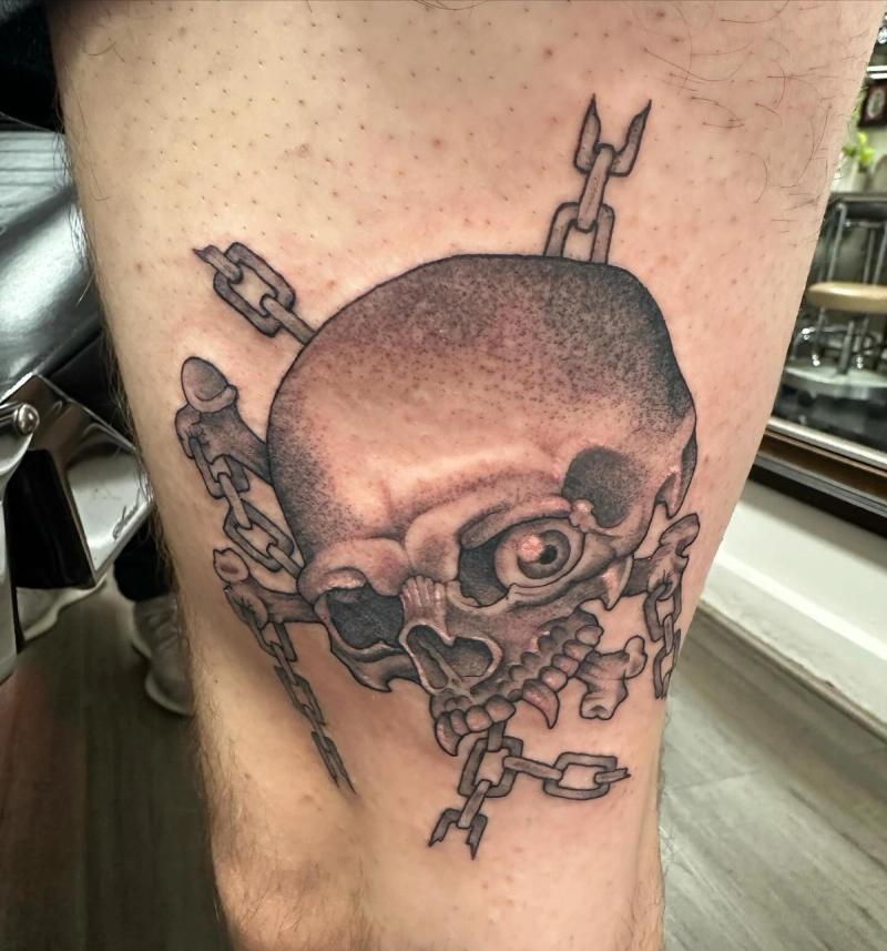 Black and grey skull and chains tattoo on thigh