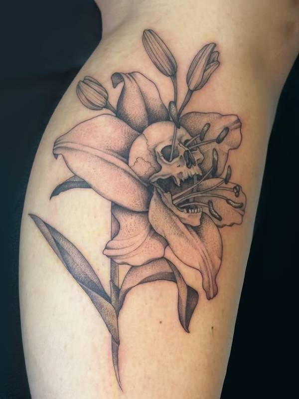 Black and grey skull and lily tattoo on forearm