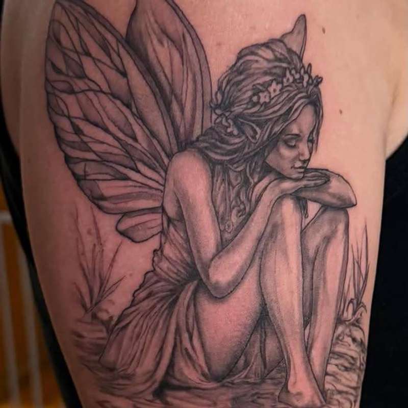 Black and grey realistic fairy tattoo on upper arm
