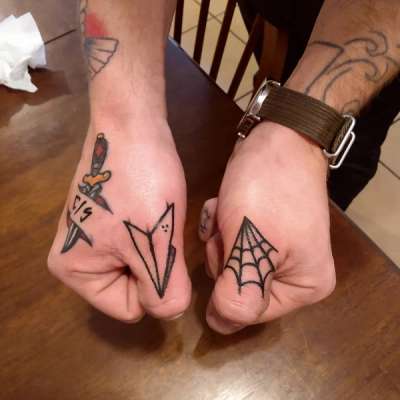 minimalist tattoos on hands featuring dagger, paper plane, and spider web