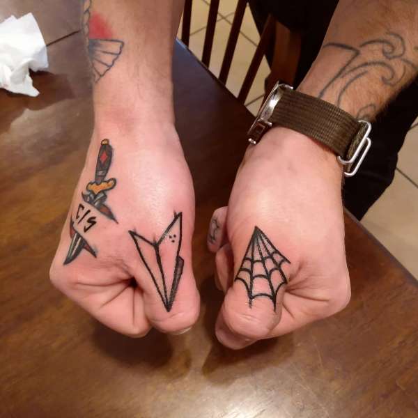 minimalist tattoos on hands featuring dagger, paper plane, and spider web