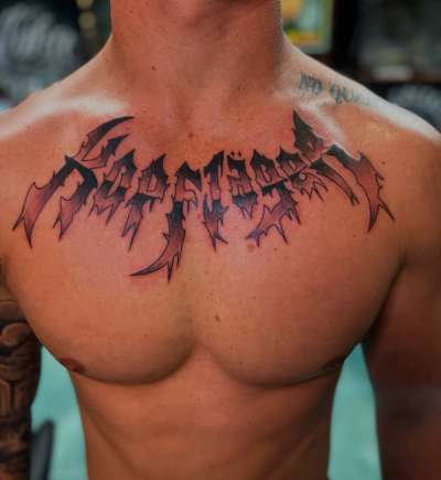 demon slayer lettering tattoo on chest with wing details