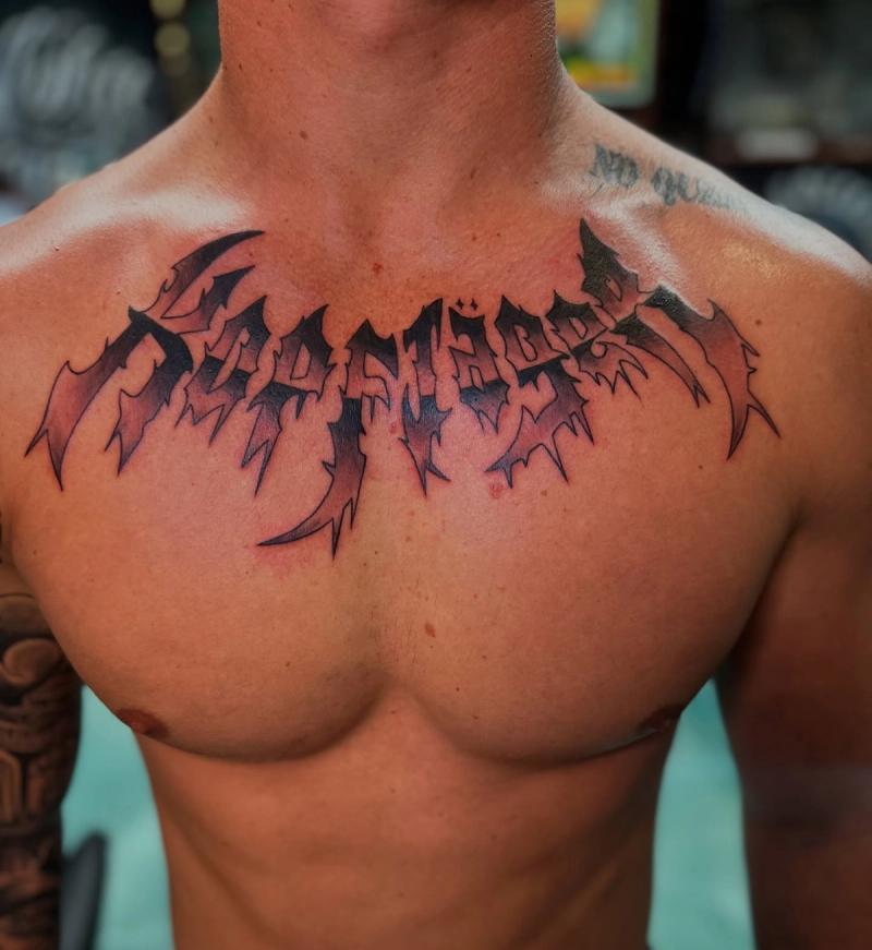 demon slayer lettering tattoo on chest with wing details