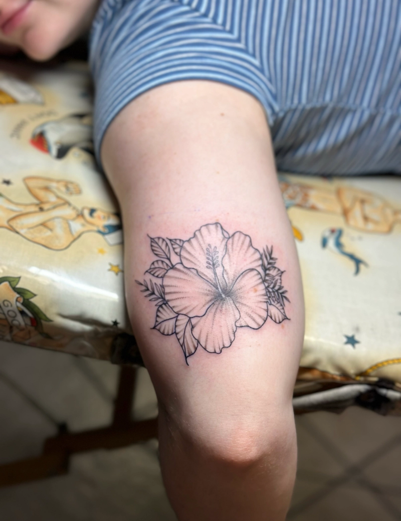 Black and grey fine line hibiscus tattoo on upper arm
