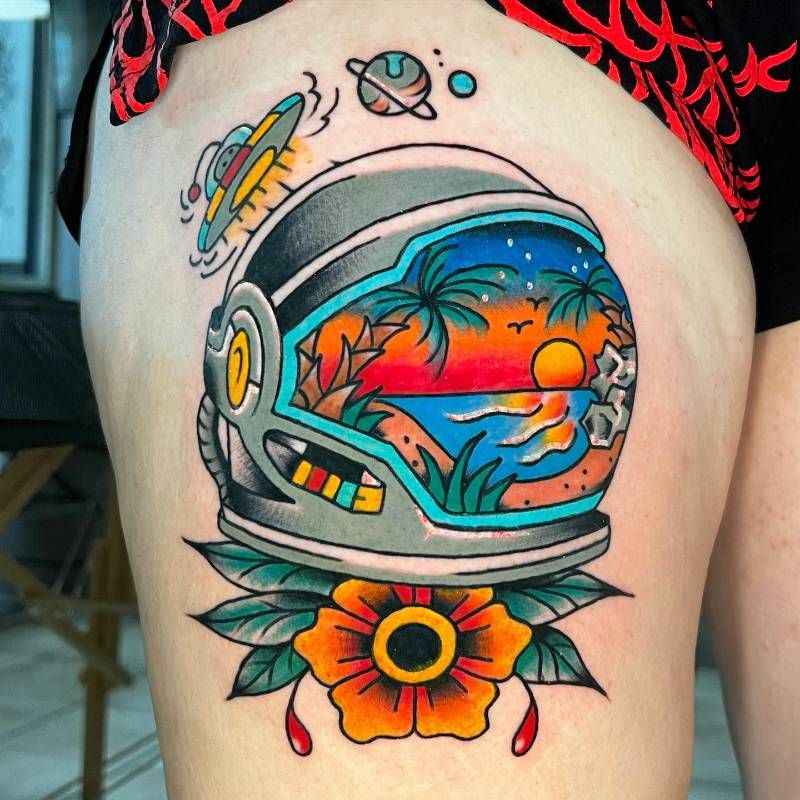 colorful astronaut helmet and sunset tattoo on thigh
