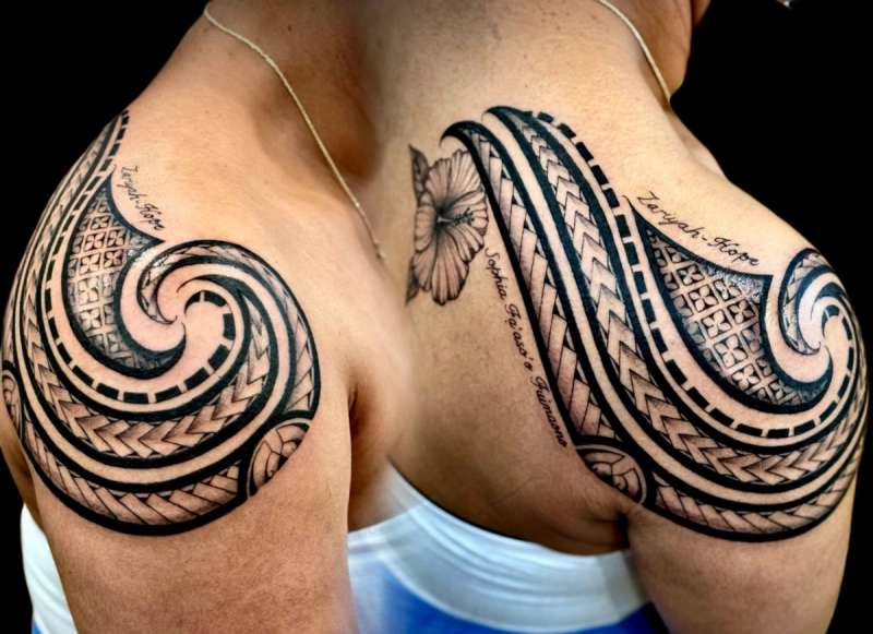 Black and grey tribal tattoo with lettering on shoulder