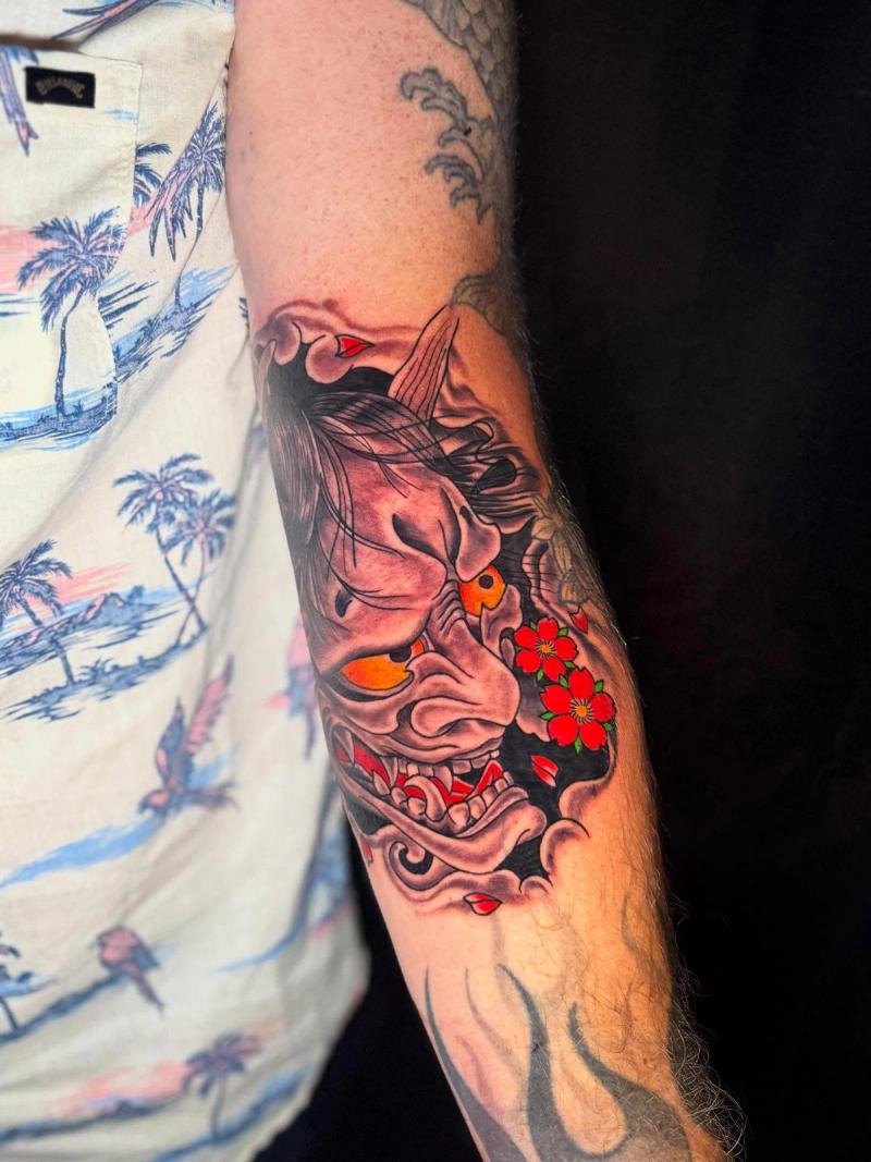 colorful oni mask forearm tattoo with cherry blossoms and traditional japanese elements