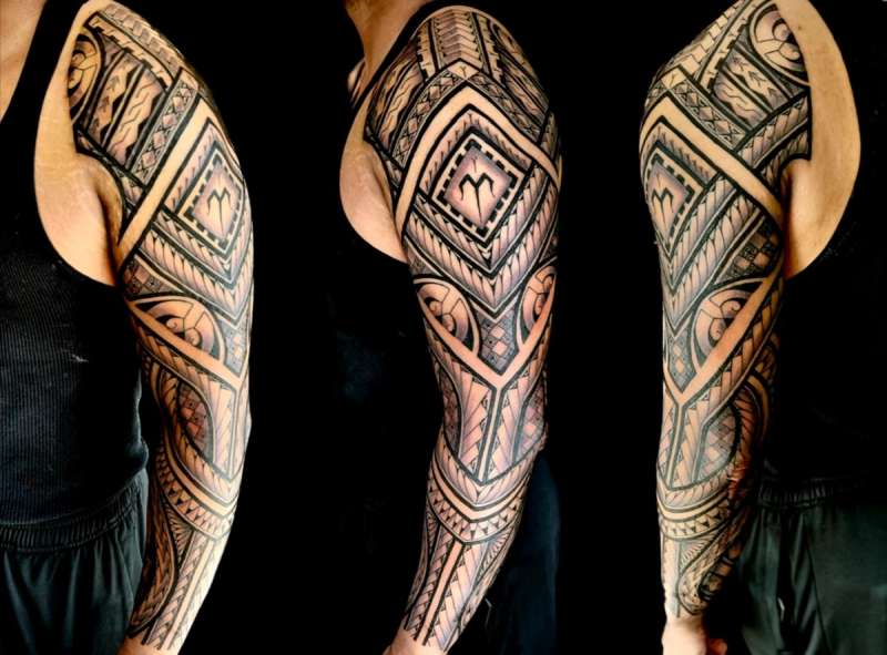Black and grey tribal geometric full sleeve tattoo on arm