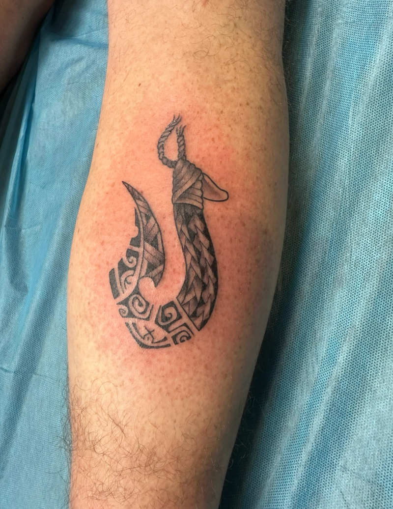 Black and grey tribal hook tattoo on calf