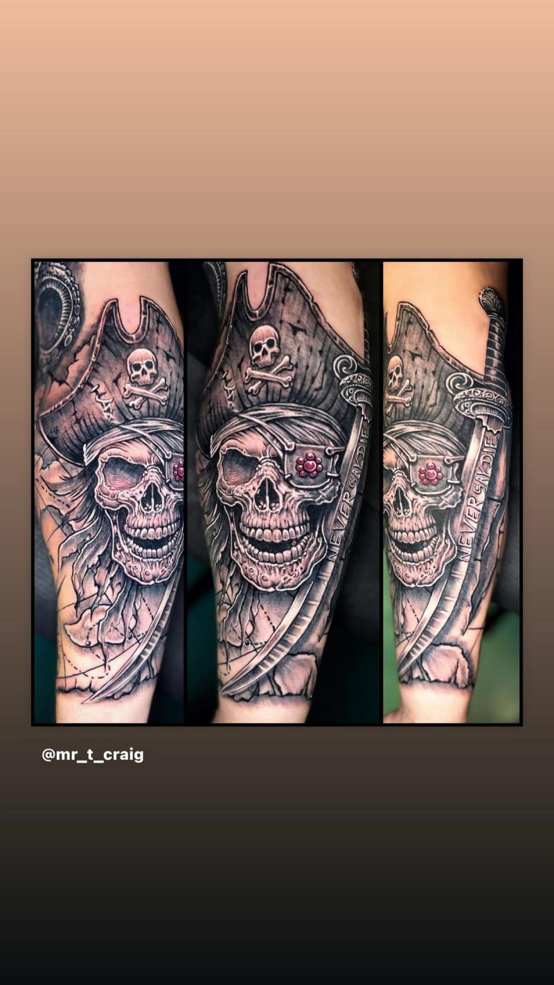 Realistic and illustrative pirate skull tattoo on forearm.