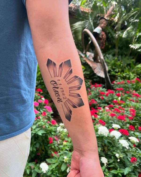 tribal sun design with lettering on forearm