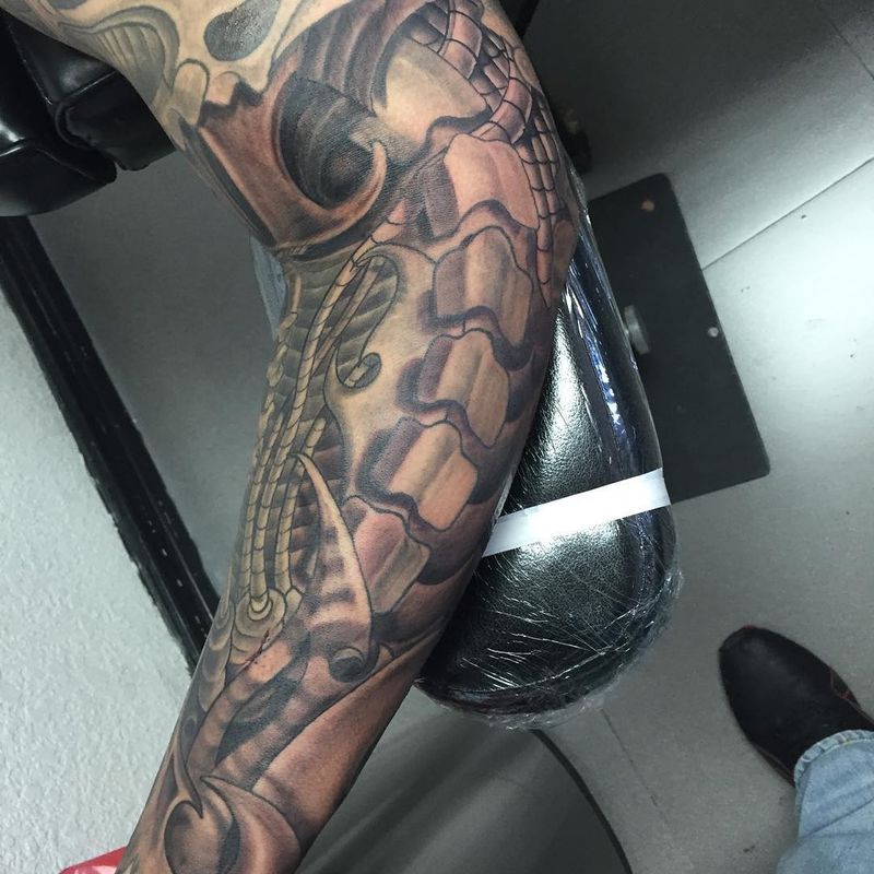 Black and grey illustrative snake and skull full sleeve on arm