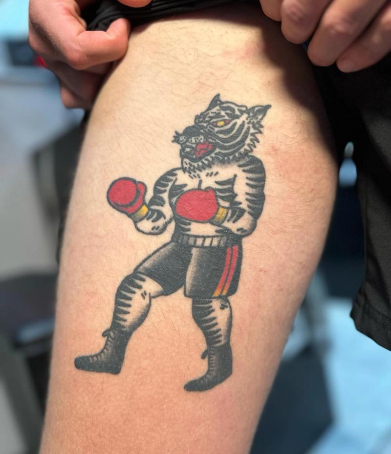 traditional tattoo of a tiger in boxing gloves on a thigh