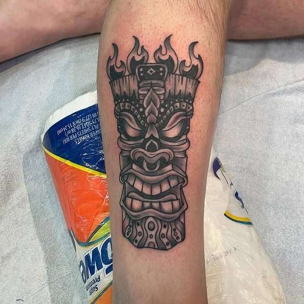 Black and grey tribal mask tattoo on calf