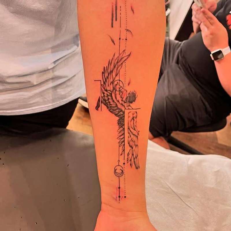 Black and grey fine line winged figure with geometric elements on forearm