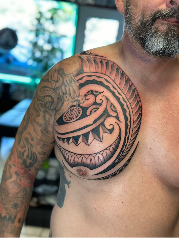 Tribal blackwork tattoo covering the upper chest