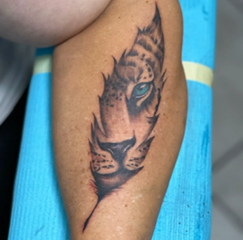 Color illustrative leopard face tattoo on calf.