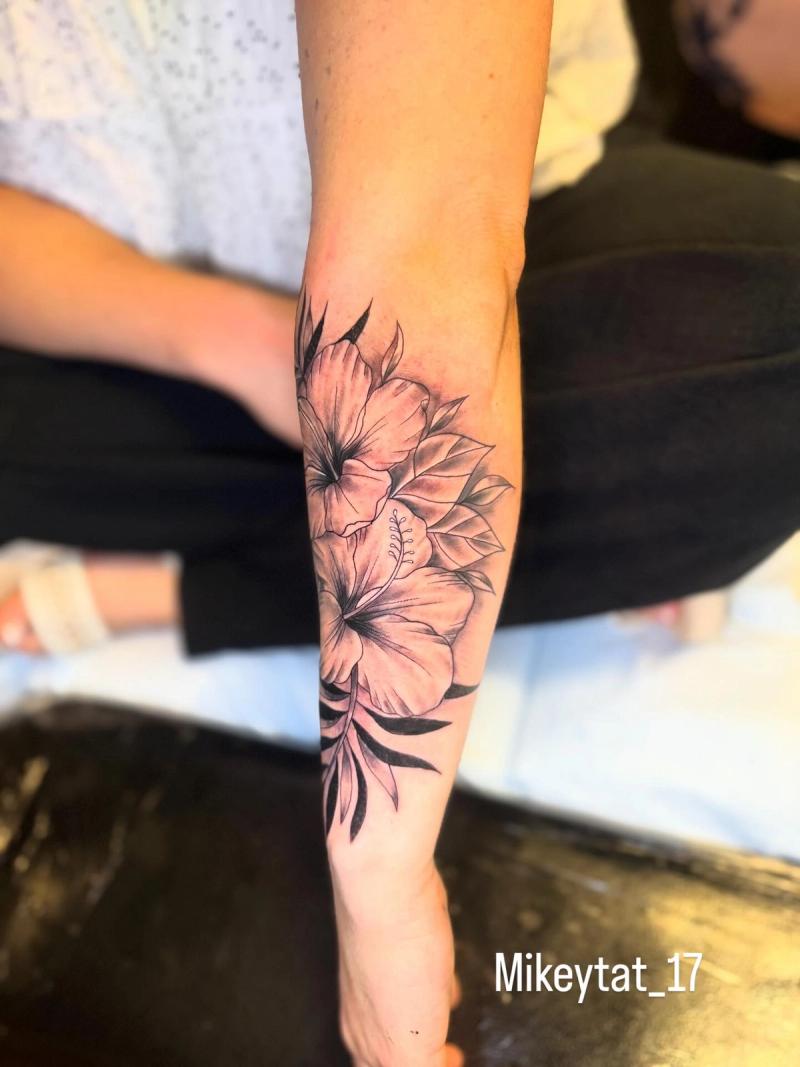 hibiscus flower forearm tattoo with botanical leaves