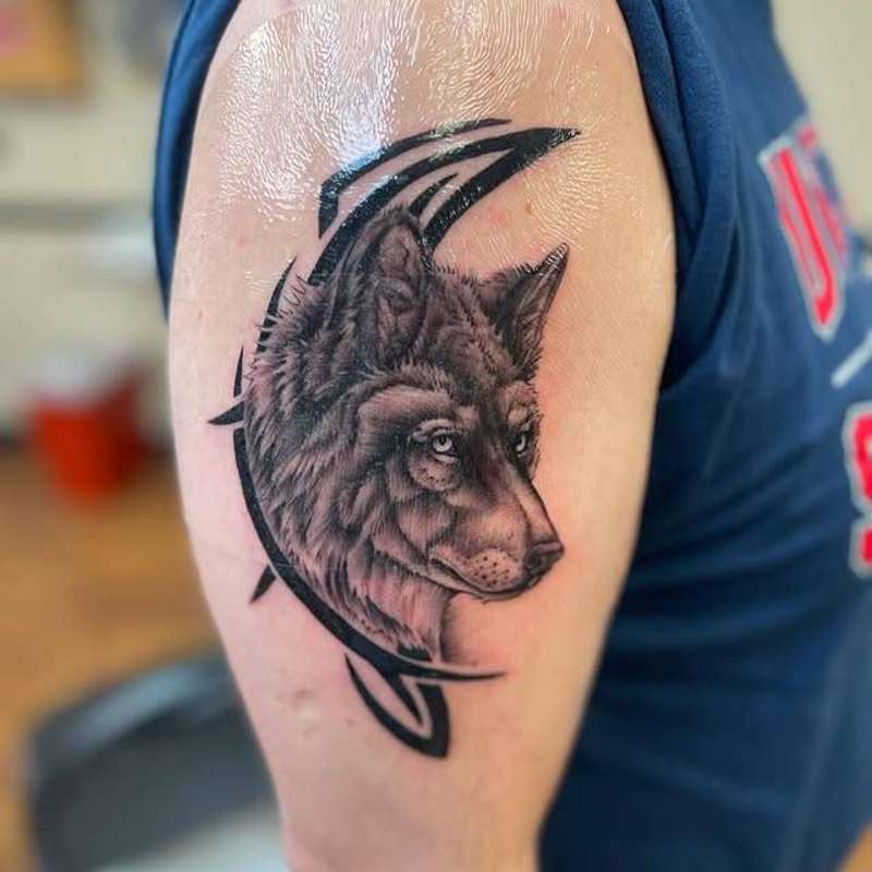 wolf head tattoo on upper arm in black and grey