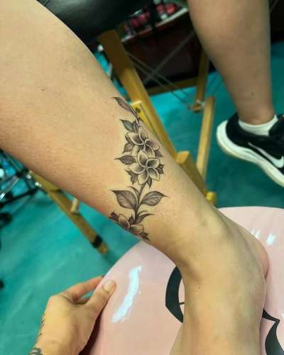 Black and grey fine line floral tattoo on calf