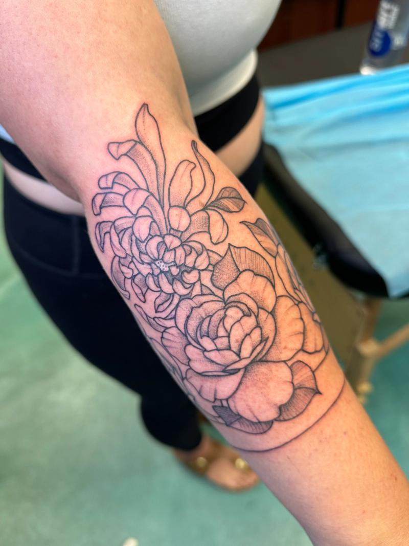 Blackwork botanical tattoo of flowers on forearm