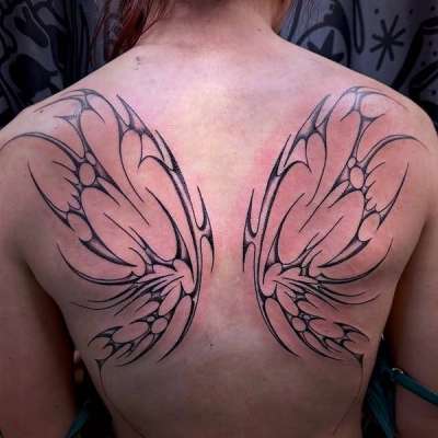 Blackwork tribal wing design on upper back
