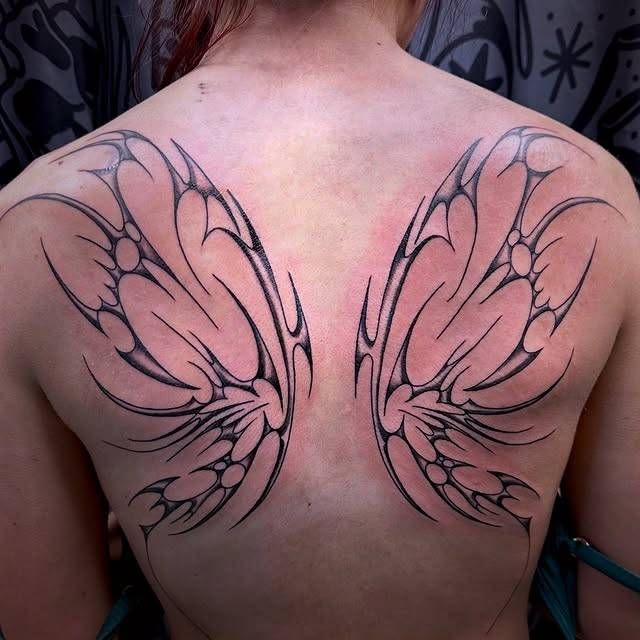 Blackwork tribal wing design on upper back