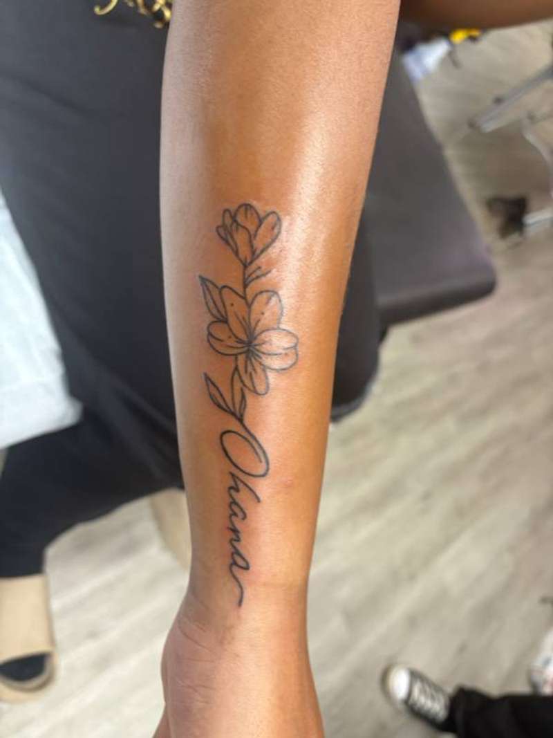 script and flower tattoo on forearm