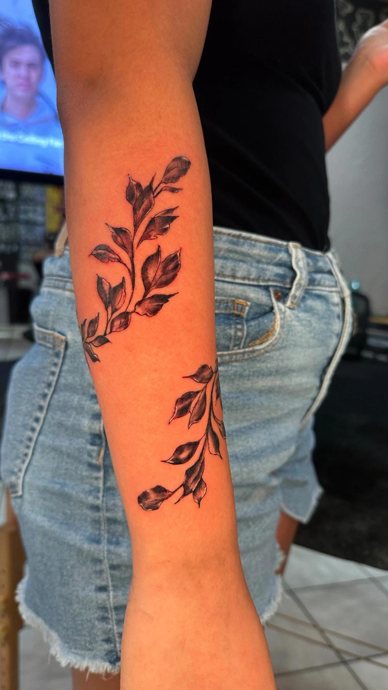 forearm tattoo of black leaves