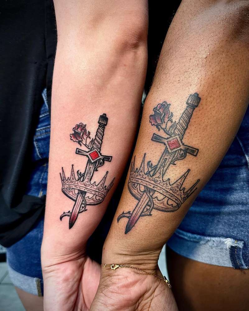 traditional sword and crown tattoo on forearms