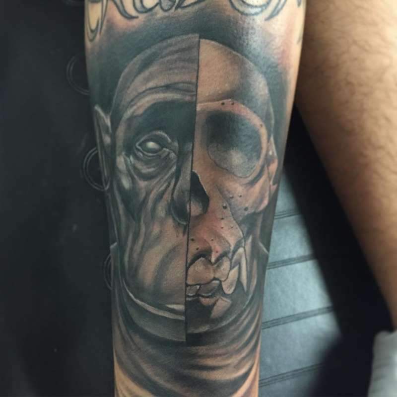 Black and grey realistic split face skull tattoo on forearm