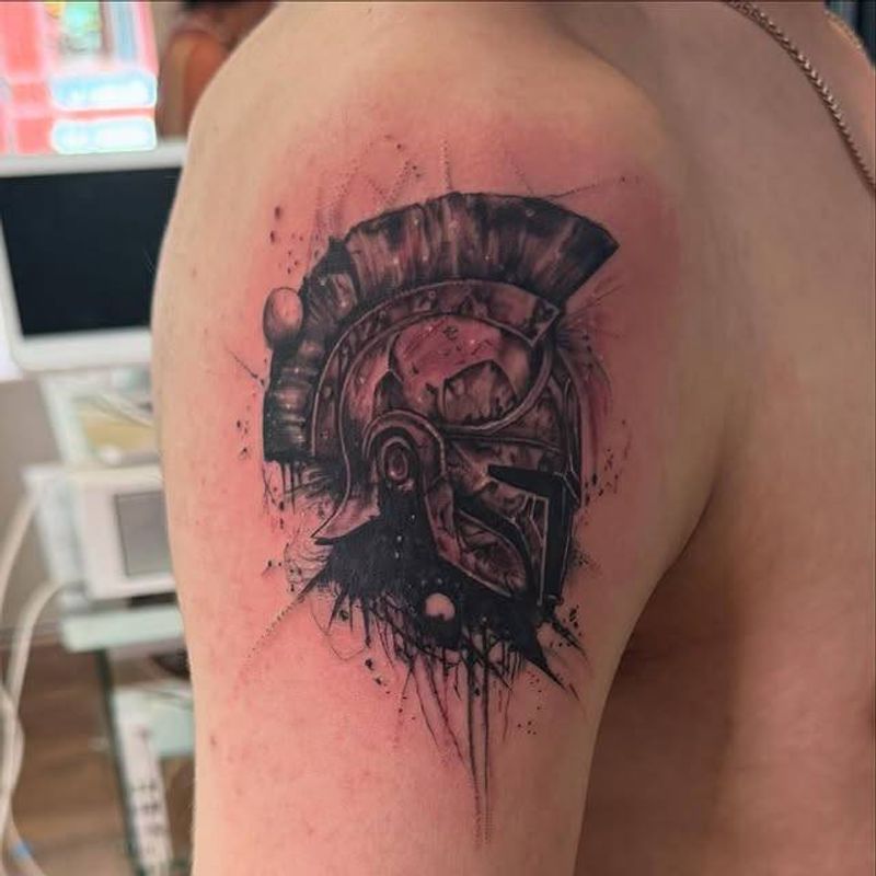 Black and grey illustrative Roman helmet tattoo on upper arm