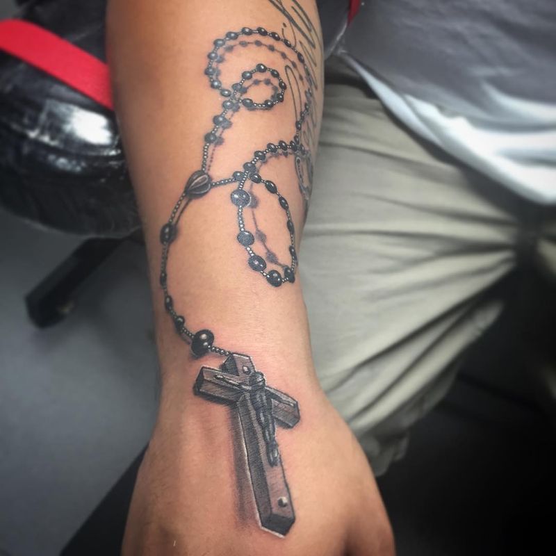 Black and grey illustrative rosary with cross on forearm