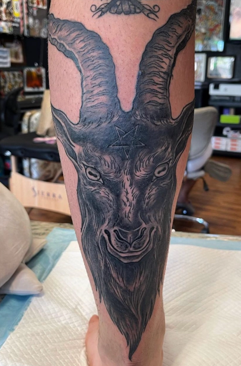 Black and grey illustrative goat head tattoo on calf