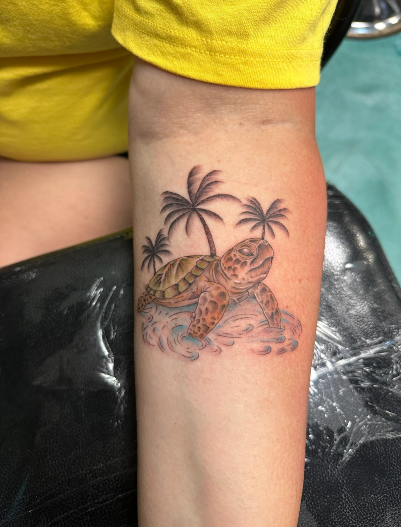 Colorful sea turtle tattoo with palm trees on forearm