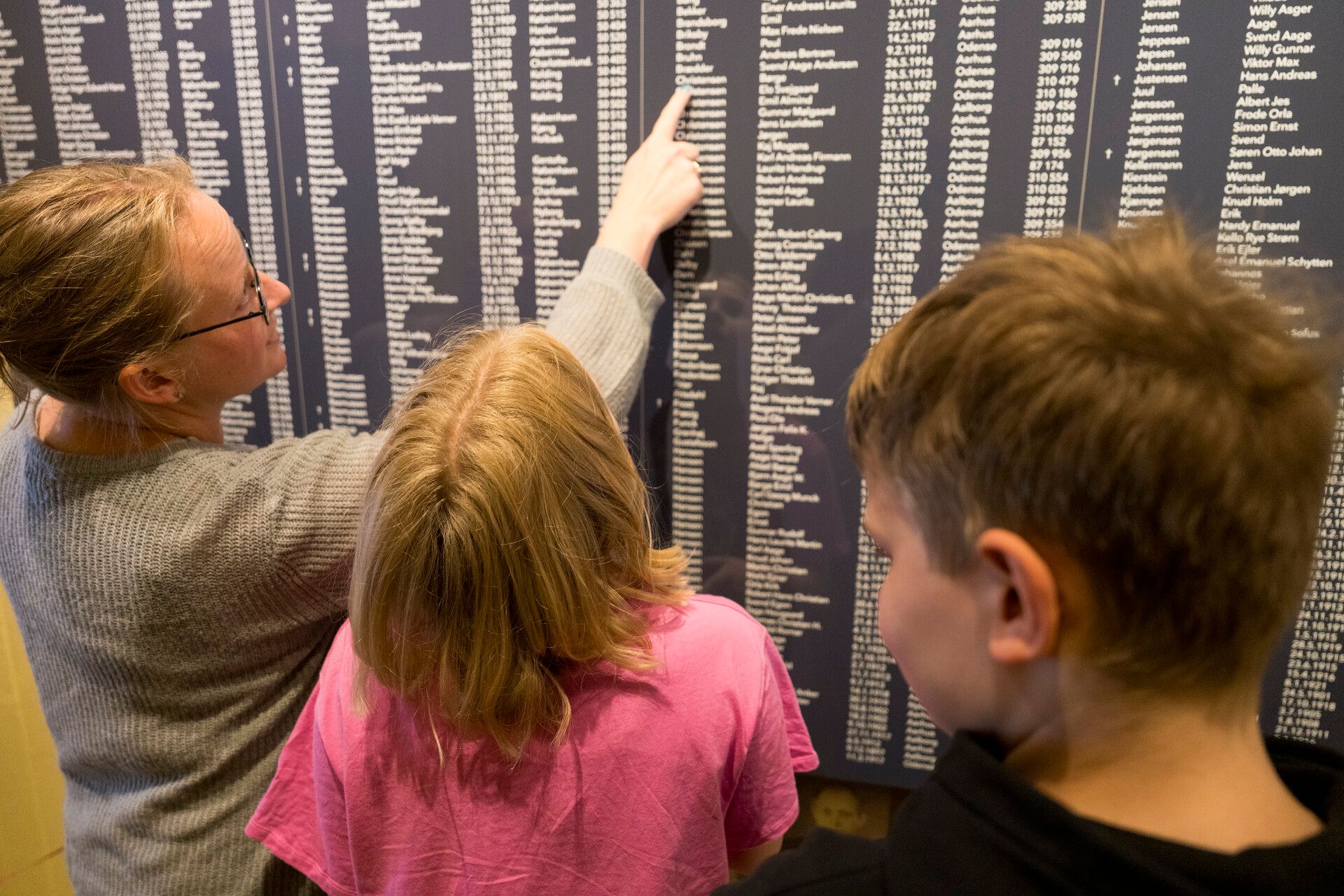 Gæster kigger på tavle med navnene på dem, der blev holdt fanget i Frøslevlejren