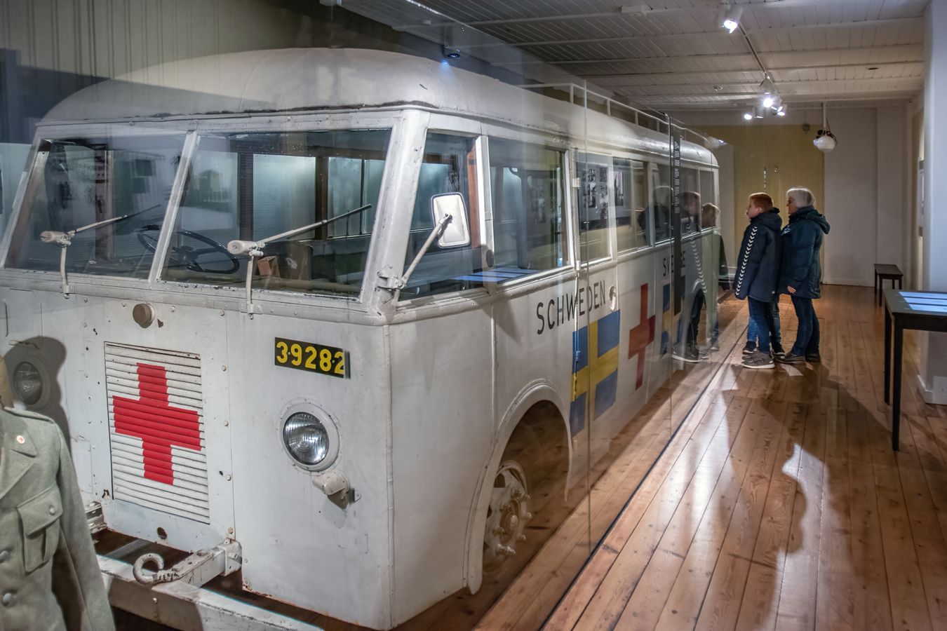 Two guests look at the white bus in the exhibition at Frøslev Camp.